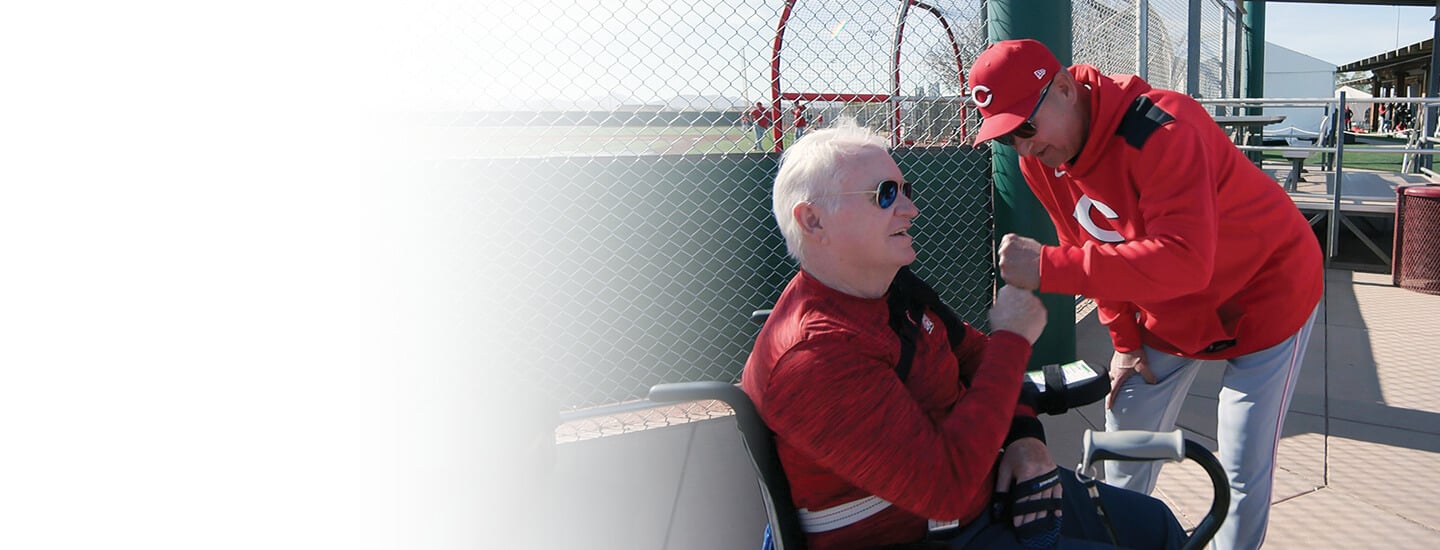 A baseball coach giving a fist bump to a man in a wheelchair.
