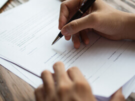 Close-up view of hand holding pen and signing paper.