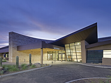 Exterior view of hospital entrance against purple evening sky.