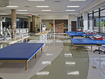 Interior view of patient therapy gym with beds and equipment.